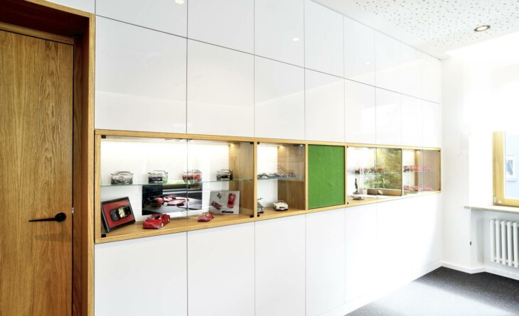 a white cupboard with a glass display where red model cars are shown