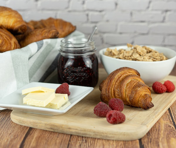 breakfast with cereal and croissants, butter, raspberries and jam